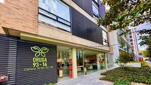 Um edifício moderno com uma placa que diz "ORUGA 93-16" e "Carrera 16 No. 93 99".