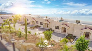 A resort with multiple buildings, outdoor spaces, and a view of the sea.