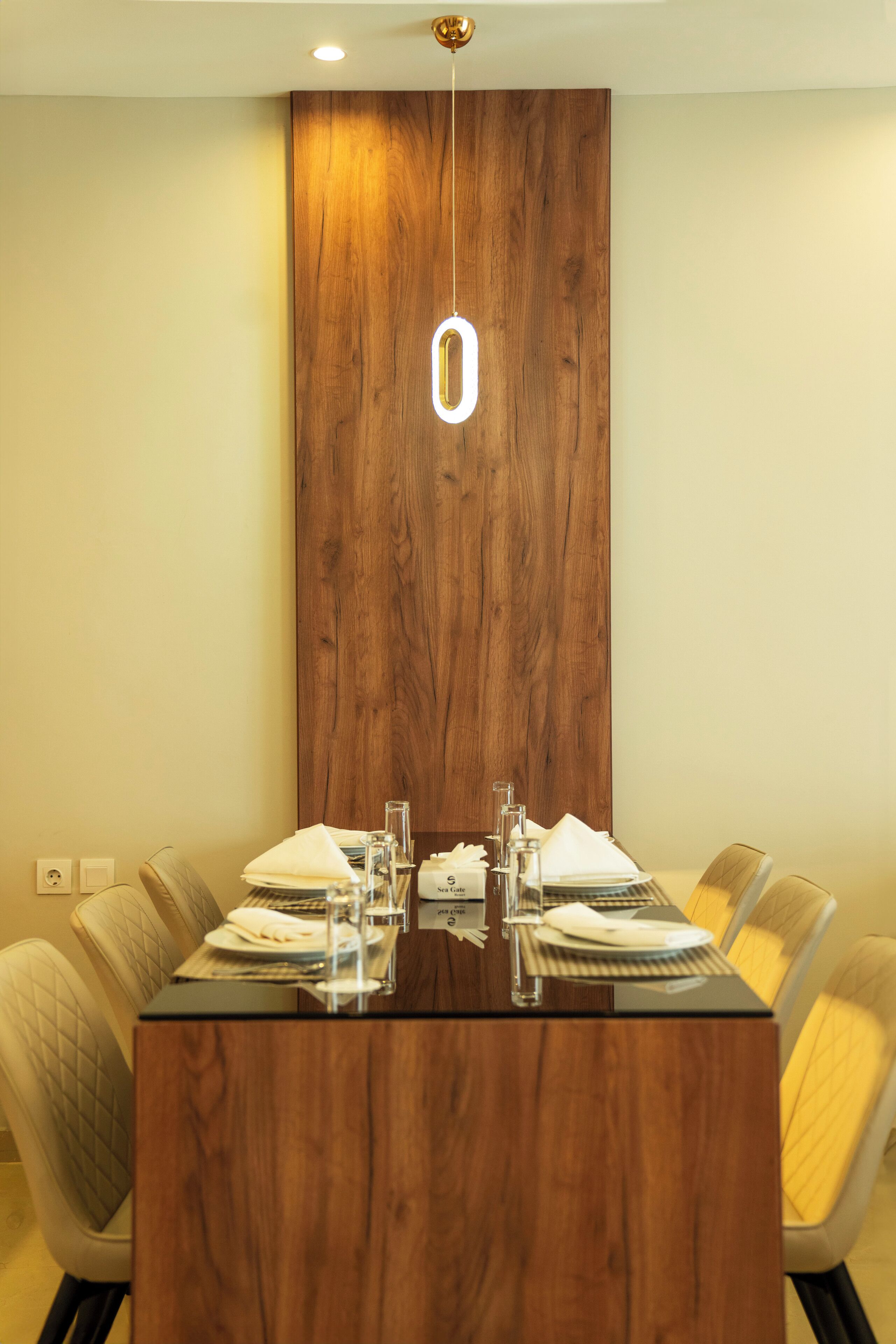 A conference table with a wooden finish, surrounded by upholstered chairs with a quilted pattern.