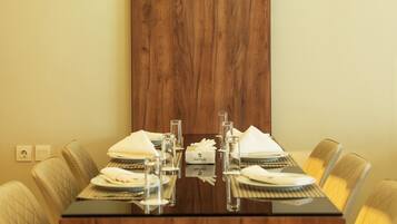A conference table with a wooden finish, surrounded by upholstered chairs with a quilted pattern.