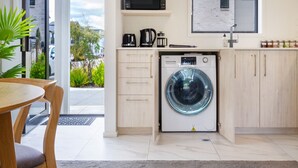 Une cuisine moderne équipée d’un lave-linge intégré, d’un four à micro-ondes et d’une machine à café.