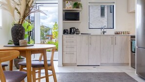 Une cuisine moderne avec des meubles de couleur bois clair, un four à micro-ondes encastré et un réfrigérateur en acier inoxydable.