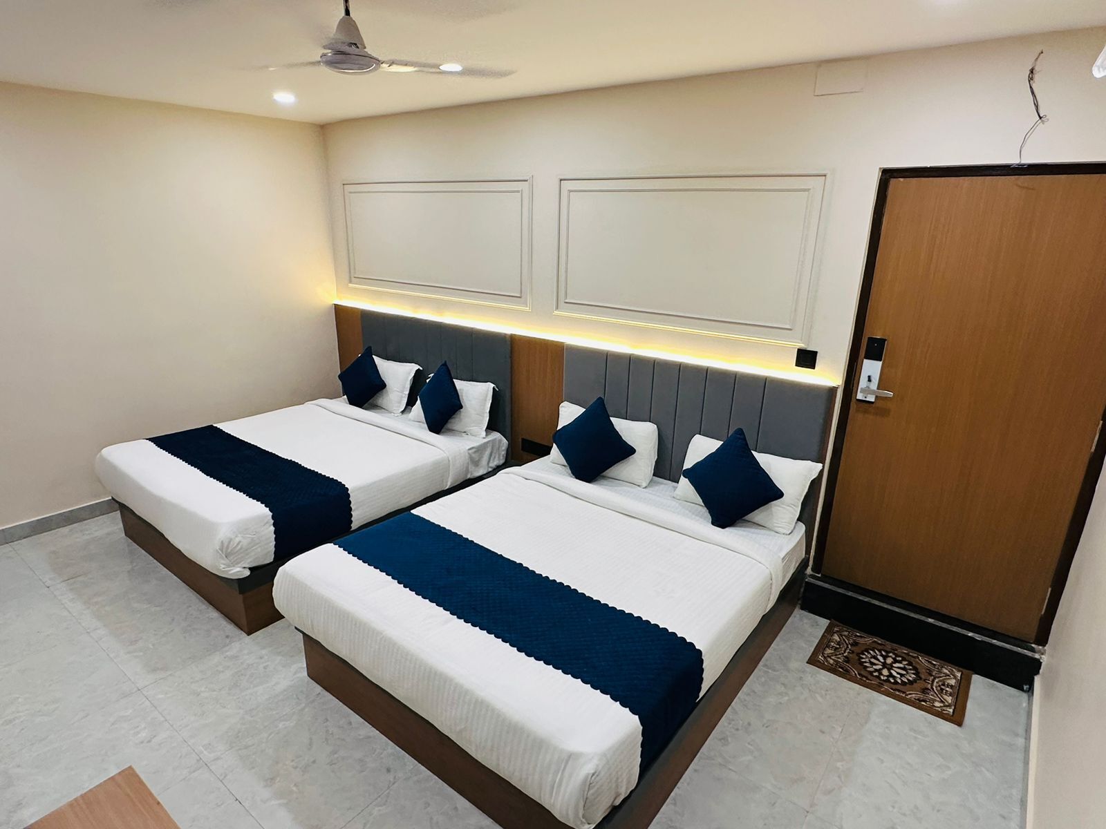 A hotel room with two beds, a wooden door, and a ceiling fan.