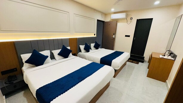 Habitación de hotel con dos camas, un escritorio, un armario y un ventilador de techo.