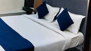 Una habitación de hotel con cama, mesita de noche, equipo de aire acondicionado y una puerta.
