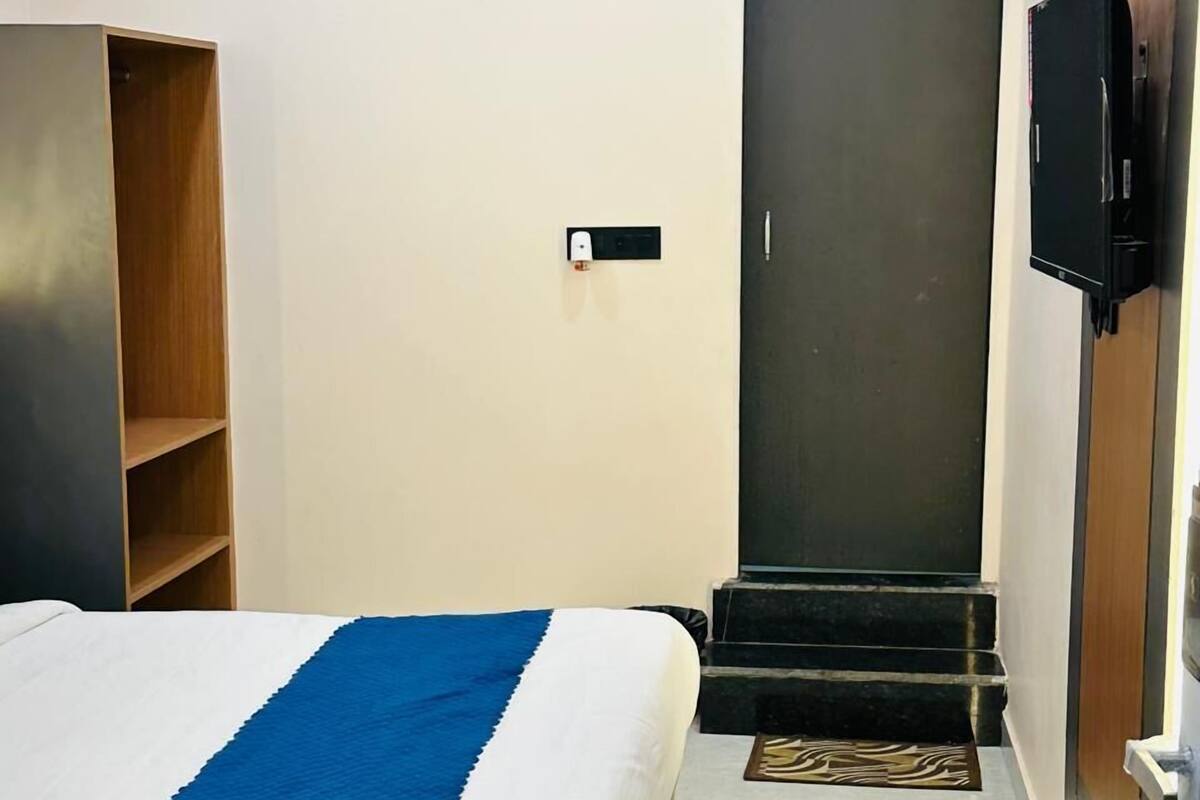 Ein Hotelzimmer mit Bett, Kleiderschrank, Fernseher und einer Tür.