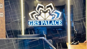 Un mostrador de recepción con un cartel que dice "GRS PALACE" y una piscina al frente.