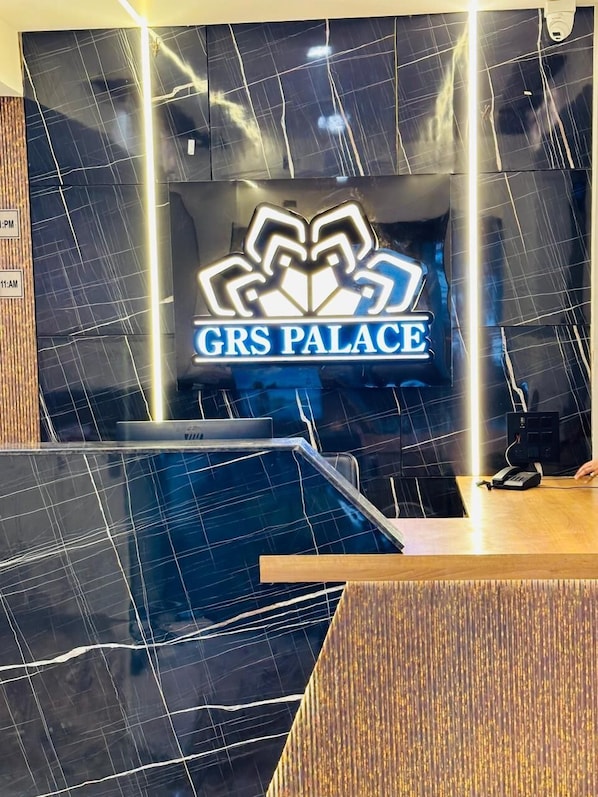 A reception desk with a sign reading "GRS PALACE" and a pool area in the foreground. - Hotel grs palace (Varanasi)