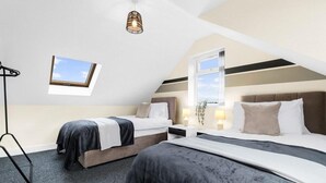 A modern bedroom with two beds, a skylight, and a view of the sky.