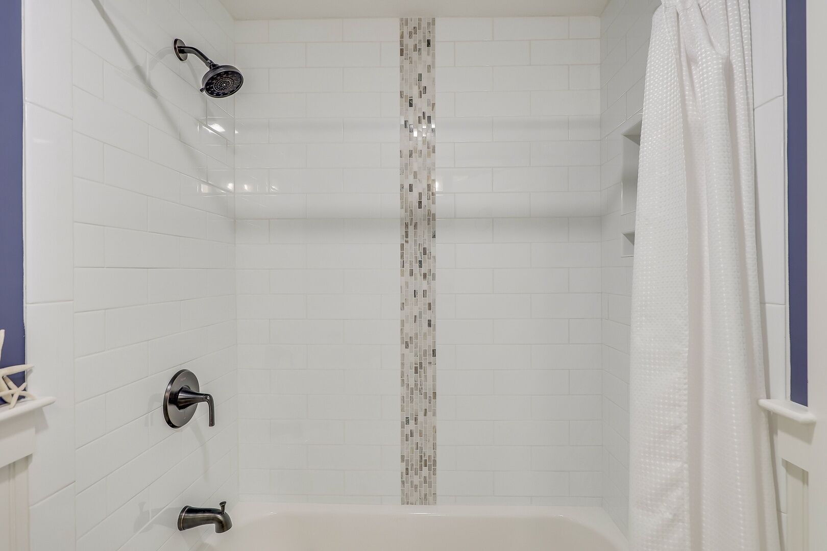 Een douche met een handdouche, een wandmengkraan en een betegelde douchecel.