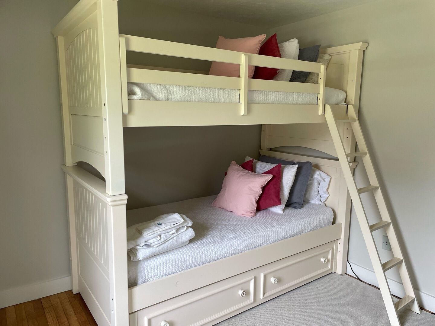 Een stapelbed met een ladder, kussens en opgevouwen dekens.