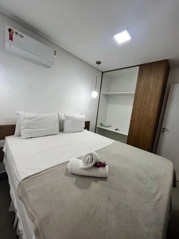 A hotel room with a neatly made bed, a large mirror, and a wooden wardrobe. - Green Porto 02 (Ipojuca)