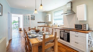 A kitchen with wooden flooring, white cabinets, a microwave, and a stove.