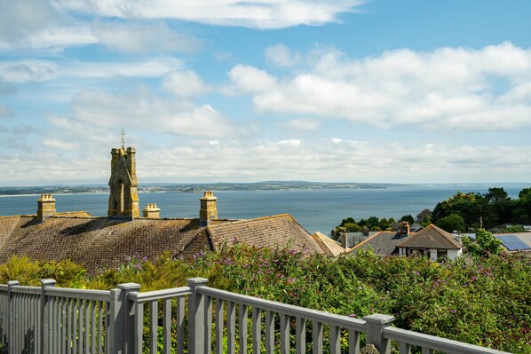 A coastal town with stone buildings, a prominent tower, and a view of the sea.