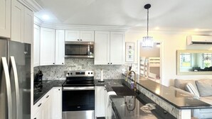 A modern kitchen with white cabinetry, stainless steel appliances, a wooden floor, and a central island.