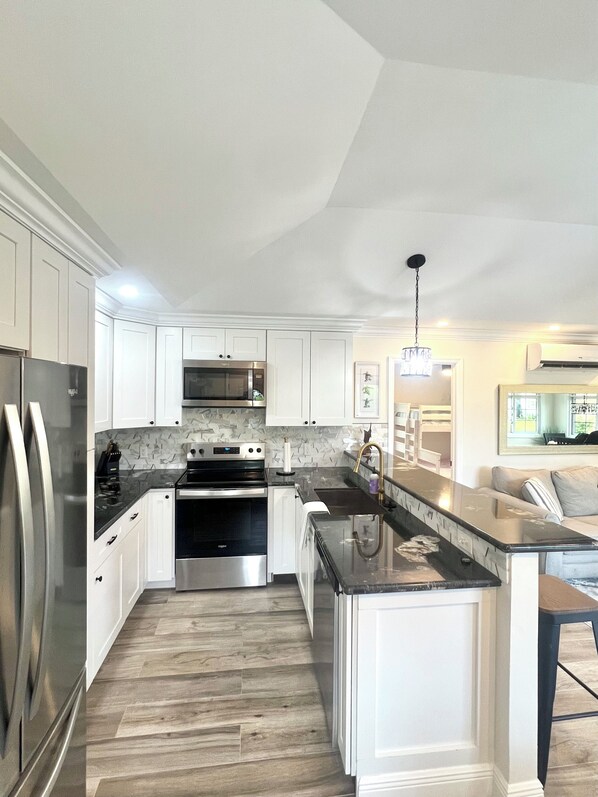 A modern kitchen with white cabinetry, stainless steel appliances, a wooden floor, and a central island.