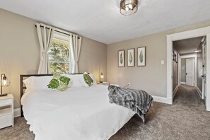 Cozy retreat with a large bed, nightstand, and framed artwork.