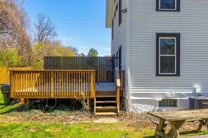 Enjoy the serene backyard with a wooden deck, bench, and stairs leading to a covered area.