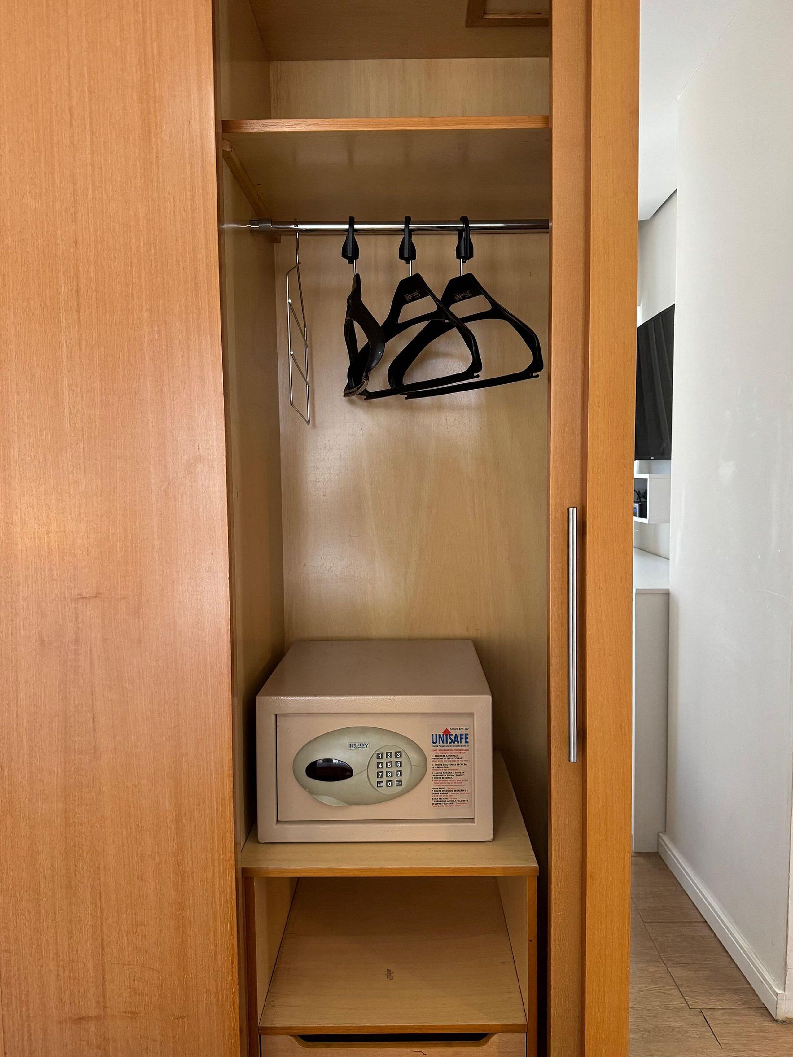 A wooden closet with a built-in safe, a shoe rack, and a small shelf.
