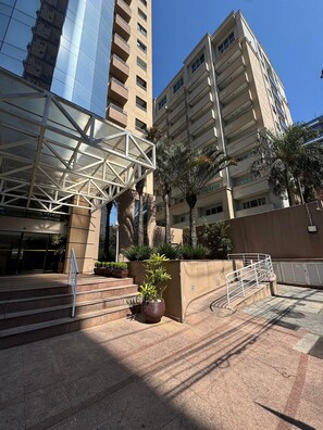 A modern building with a glass facade, a metal staircase, and a potted plant in the foreground. - Get a Flat 601 Ibirapuera -Jardins (São Paulo)