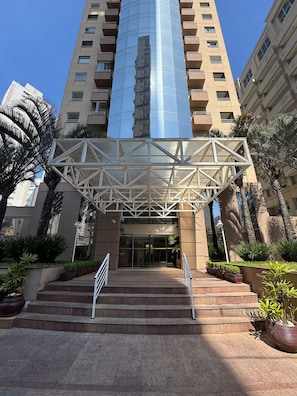A modern building with a glass facade and a geometric entrance structure. - Get a Flat 601 Ibirapuera -Jardins (São Paulo)