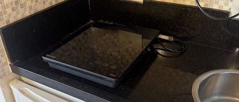 A kitchen with a black countertop, a white refrigerator, and a stainless steel sink.