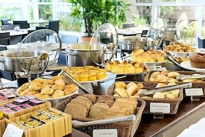 A buffet with various food items including breads, pastries, and a selection of cheeses. - Get a Flat 601 Ibirapuera -Jardins (São Paulo)