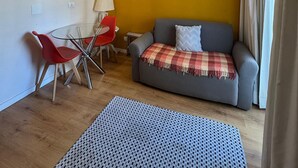 A small living area with a sofa, a red chair, a glass table, and a lamp. - Get a Flat 601 Ibirapuera -Jardins (São Paulo)