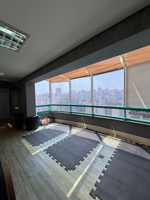 A room with large windows, a view of a cityscape, and tatami mats on the floor.