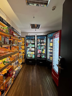 A store interior with shelves stocked with snacks and beverages, and two refrigerated display cases.