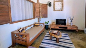 Una sala de estar acogedora con un sofá, una mesa de centro, un televisor y una mesita auxiliar.