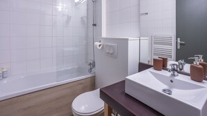 Uma casa de banho moderna com banheira, sanita e lavatório.