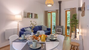 Una sala de estar moderna con comedor, sofá, chimenea y vistas al exterior.