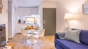 Un espacio habitable compacto con comedor, kitchenette y un sofá con lámpara.