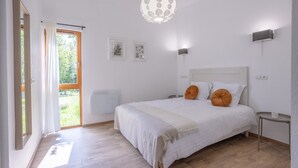 Un dormitorio con cama, mesita de noche, lámpara y ventana con cortinas.