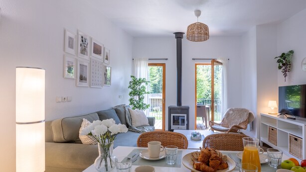 Una sala de estar acogedora con sofá, mesa de comedor y chimenea. Hay cuadros en la pared y un televisor sobre un mueble.