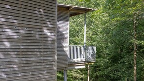 Eine Holzhütte mit einem Balkon mit Blick auf ein bewaldetes Gebiet.