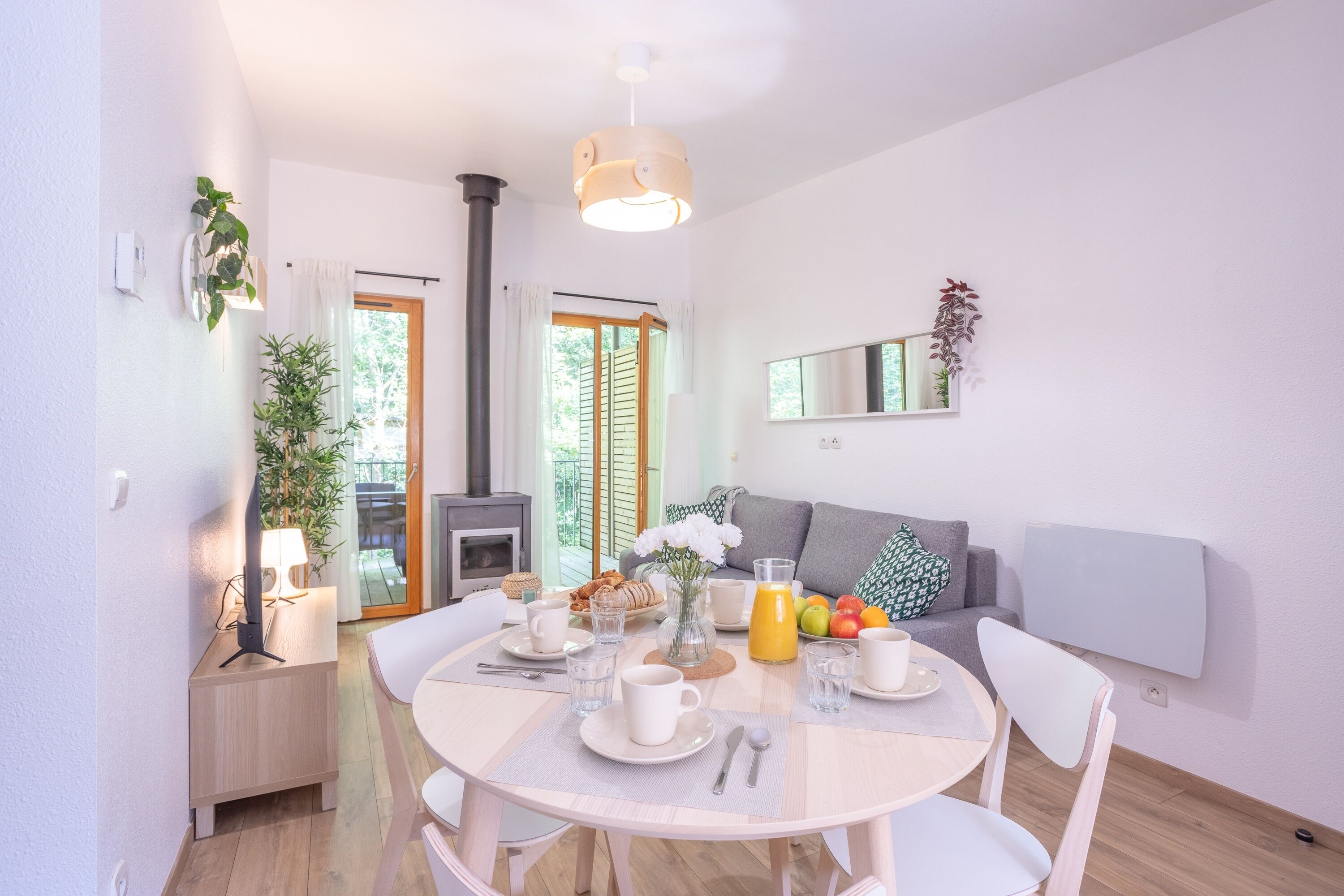 A modern dining area with a round table, white chairs, and breakfast items.