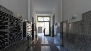 Un couloir avec une rangée de boîtes aux lettres sur le côté gauche et une porte au fond.