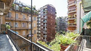 Un immeuble résidentiel à plusieurs étages, doté de balcons, dont certains sont ornés de plantes.