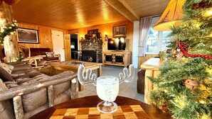 Un acogedor interior de cabaña con chimenea, muebles de madera y un árbol de Navidad.