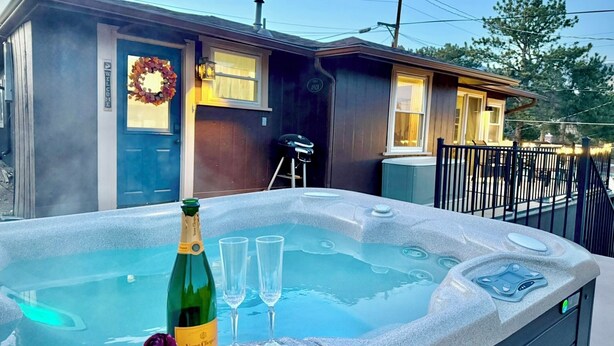 A hot tub with a bottle of Veuve Clicquot champagne and two glasses, a "Welcome" sign, and a wreath on a house.