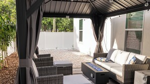 Eine Terrasse im Freien mit Korbmöbeln, einer Couch und einer Feuerstelle.