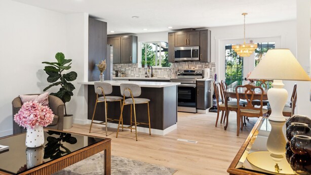Una cocina moderna con una isla central, taburetes de bar y una zona de comedor con mesa y sillas.