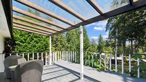 Terraza exterior techada con muebles de mimbre y vista a un área boscosa.