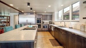 Een moderne keuken met een centraal eiland, roestvrijstalen apparatuur en een groot raam voor natuurlijk licht.