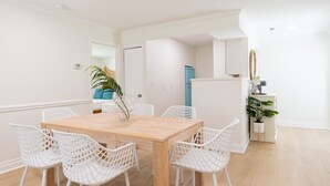 A dining area with a wooden table and white wireframe chairs, a blue refrigerator, and a potted plant. - The Juni (Cocoa Beach)