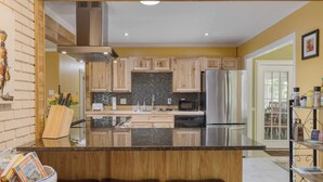 A modern kitchen with wooden cabinets, a stainless steel refrigerator, and a black tiled backsplash. - Asheville Sunset 10min to Asheville + Ping Pong (Asheville)