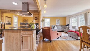 A spacious living area with a large wooden dining table, a sofa, and a kitchen with a central island. - Asheville Sunset 10min to Asheville + Ping Pong (Asheville)