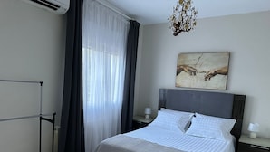 A bedroom with a bed, a nightstand, a wall-mounted artwork, and a window with sheer curtains. - VILLA LOS ALMENDROS WITH PRIVATE POOL  (Calpe , Alicante)